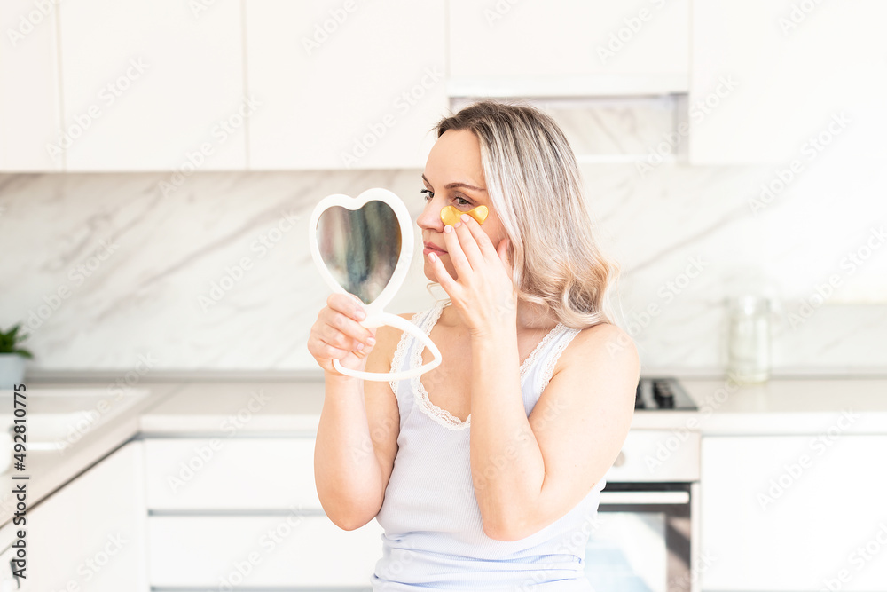 Middle age woman in pajama at kitchen with cosmetic collagen patches under eyes. Facial care. Skin cosmetology. Morning routine, Home spa and wellness, cosmetic procedures, Eye skin treatment Middle age woman in pajama at kitchen with cosmetic collagen patches under eyes. Facial care. Skin cosmetology. Morning routine, Home spa and wellness, cosmetic procedures, Eye skin treatment
