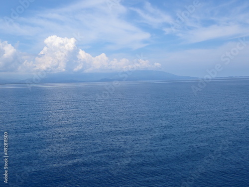 The surface of a calm sea without waves and a blue sky with clouds.