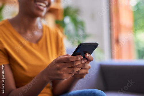 A close up cropped shot of a mobile phone being held by a young woman at home