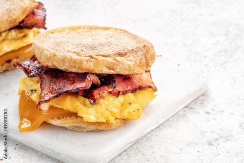 English muffin, egg, ham, and cheese breakfast sandwich on a cutting board photo