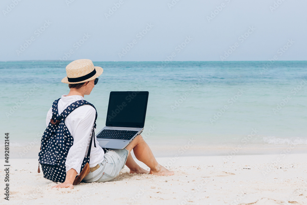 Young woman working, using laptop computer on a beach. Freelance work, vacations, distance work, social distancing, e-learning, connection, creative professional, new business, meeting online concept