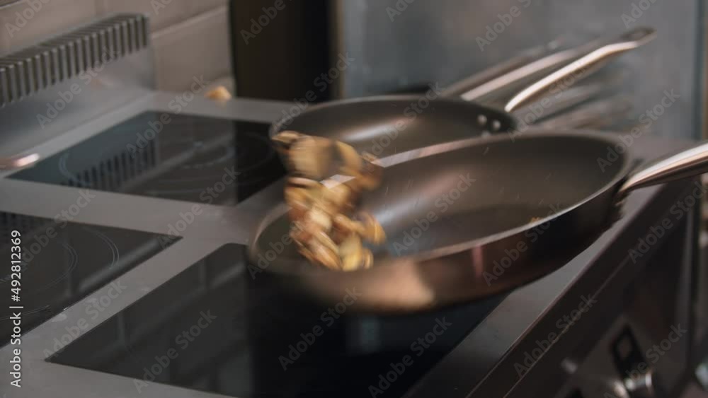 Restaurant cooking - chef roasts mushrooms in a frying pan Restaurant cooking - chef roasts mushrooms in a frying pan