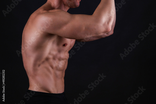 Professional bodybuilder posing over isolated white background. Front Double Biceps pose. Studio shot of a fitness trainer flexing the muscles. Close up, copy space.
