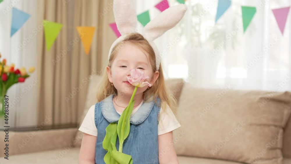 cute and funny little girl with rabbit ears holds pink tulip flower in hands cute and funny little girl with rabbit ears holds pink tulip flower in hands