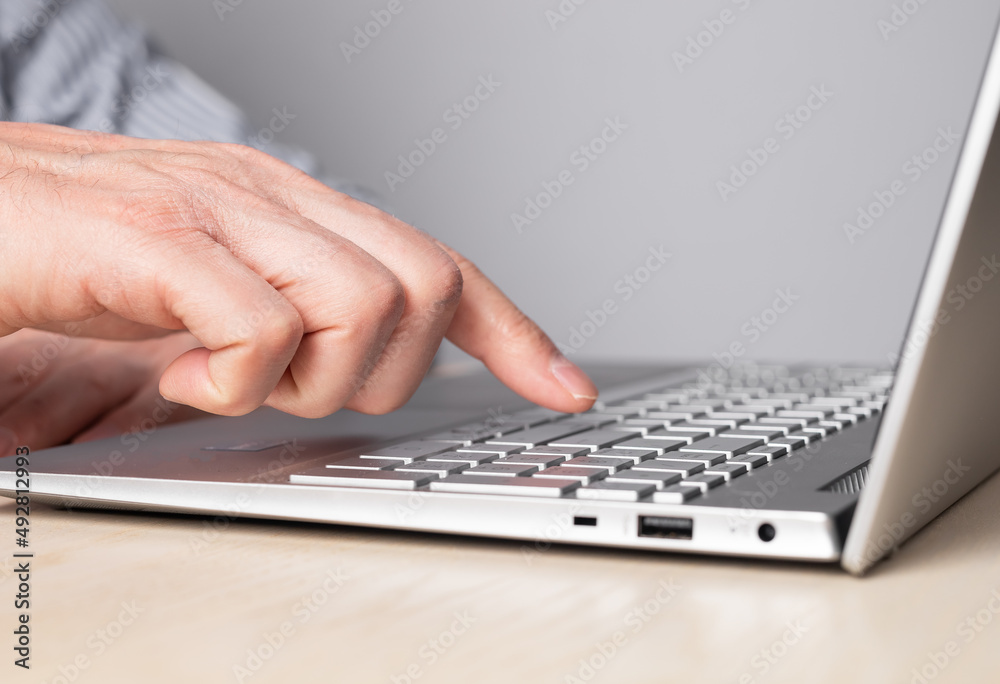Man hand closeup pressing enter key. Man sitting at table and working on laptop. High quality photo Man hand closeup pressing enter key. Man sitting at table and working on laptop. High quality photo