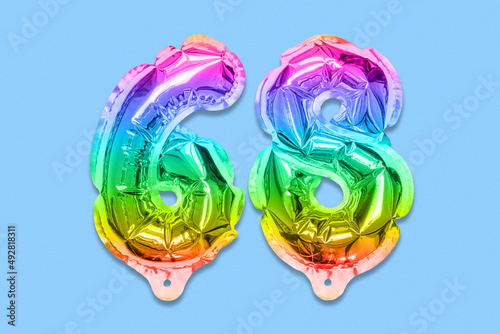 Rainbow foil balloon number, digit sixty eight on a blue background. Birthday greeting card with inscription 68. Top view. Numerical digit. Celebration event, template.