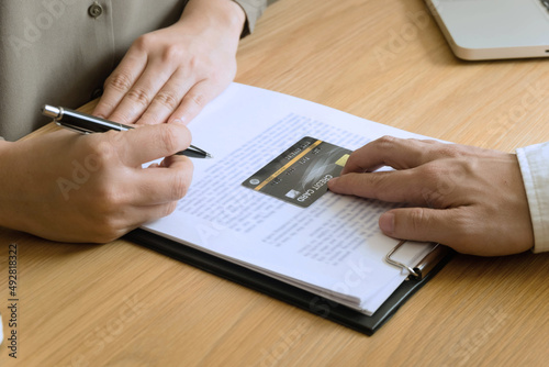Woman filling out paperwork to apply for a credit card on the table.