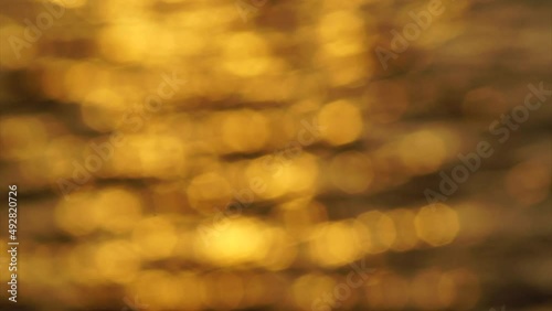 Golden bokeh light blurred background reflected on sea surf