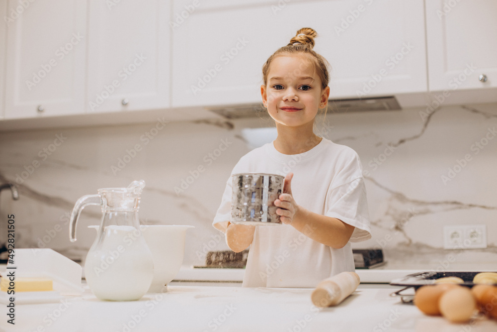 Little girl preparing dough for bakery at the kitchen