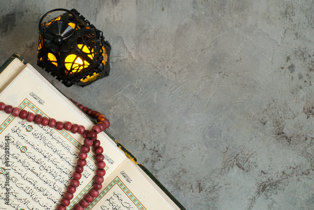 The Holy Al Quran with written Arabic calligraphy meaning of Al Quran and rosary beads or tasbih,