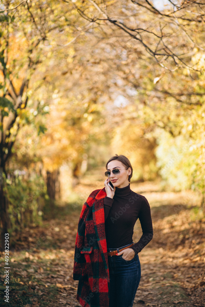 Young woman in autumn park using phone Young woman in autumn park using phone