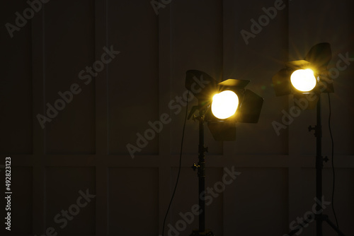 Bright yellow spotlights near wall in dark room, space for text