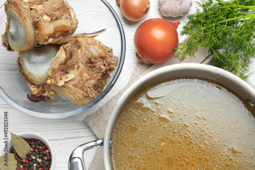 Obraz na plátně Delicious homemade bone broth and ingredients on white wooden table, flat lay