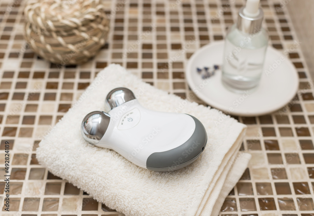 microcurrent facial toning device and beauty serum on countertop. Facial treatment, skincare, cosmetology concept. selective focus microcurrent facial toning device and beauty serum on countertop. Facial treatment, skincare, cosmetology concept. selective focus