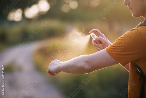 Prevention against mosquito bite in tropical destination. Man applying insect repellent on his hand.. photo