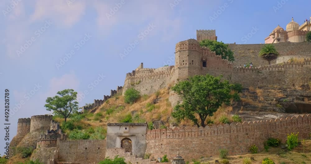 Tourists visit historic Indian Kumbhalgarh fort. Old fortress ancient walls on green Aravalli hills is famous tourist destination. Belongs to Hill forts of Rajasthan. India. Horizontal pan
