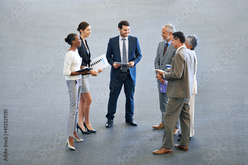 A quick briefing before the meeting. High angle shot of a group of businesspeople talking in a lobby. photo