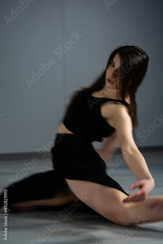 Dancer in black dress is dancing in the dark studio