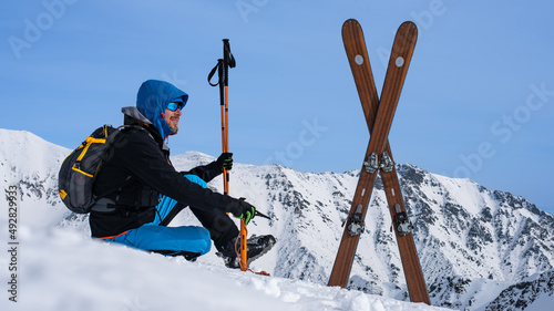 ski alpinist with skialp equipment  and outfit sitting on the snow in the high mountains. 