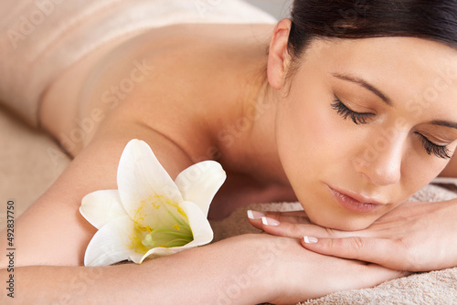 Natural beauty starts with taking time out. Cropped view of a young woman relaxing at a spa with a fresh flower nearby.