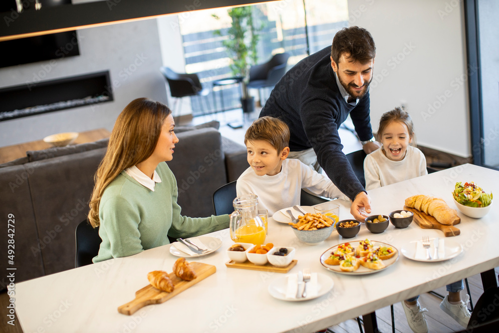 Young happy family talking while having breakfast at dining table Young happy family talking while having breakfast at dining table