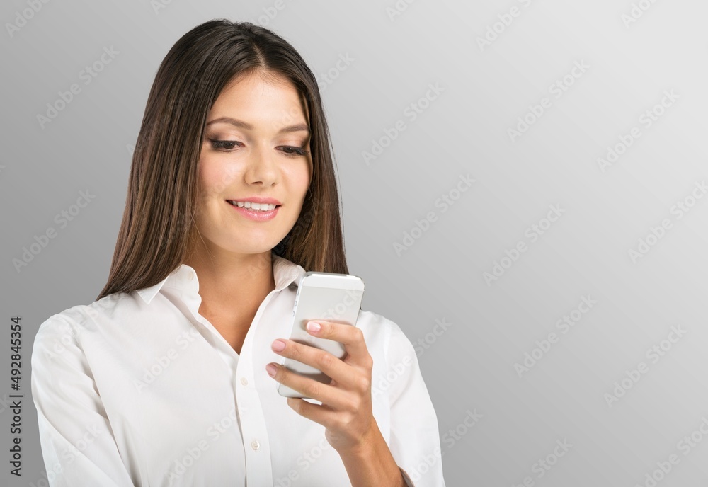 Photo of smiling woman looks with happy expression uses mobile phone for chatting online Photo of smiling woman looks with happy expression uses mobile phone for chatting online