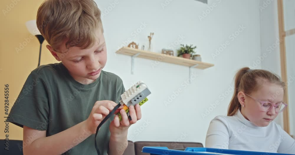 Curious kids working on a functional programable robot during robotics class at school. 