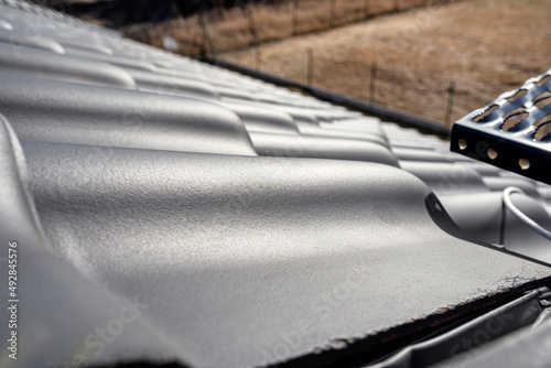The roof of a single family house is covered with new anthracite ceramic tiles, visible from above.