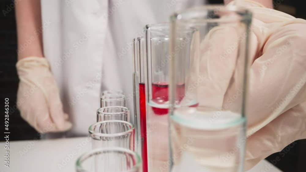 Scientist in latex gloves takes test tube with red liquid from rack in laboratory slow motion. Probe lens shot of scientific researching closeup Scientist in latex gloves takes test tube with red liquid from rack in laboratory slow motion. Probe lens shot of scientific researching closeup
