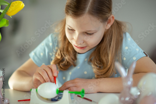 Cute teen blonde girl painting Easter eggs