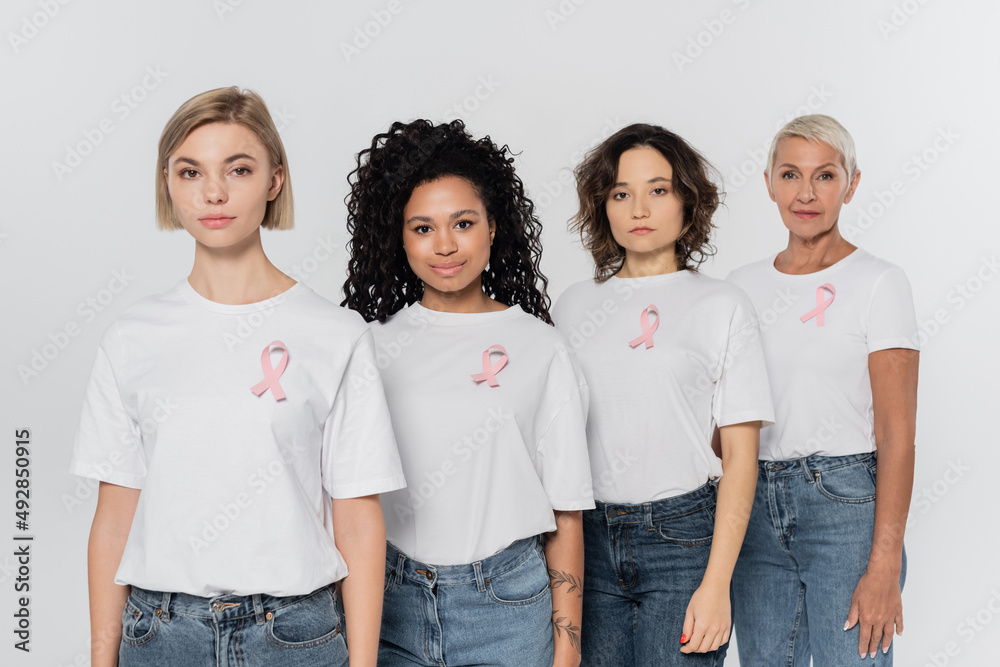 Obraz premium Multiethnic women with ribbons of breast cancer awareness standing isolated on grey.