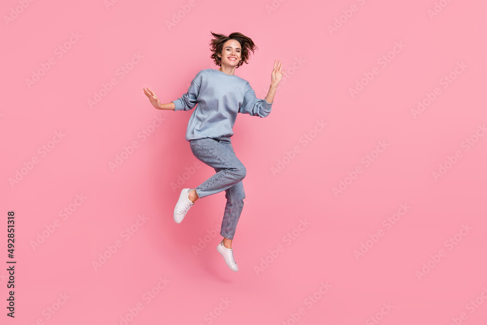 Full length photo of cool millennial lady jump wave wear jumper jeans footwear isolated on pink background Full length photo of cool millennial lady jump wave wear jumper jeans footwear isolated on pink background