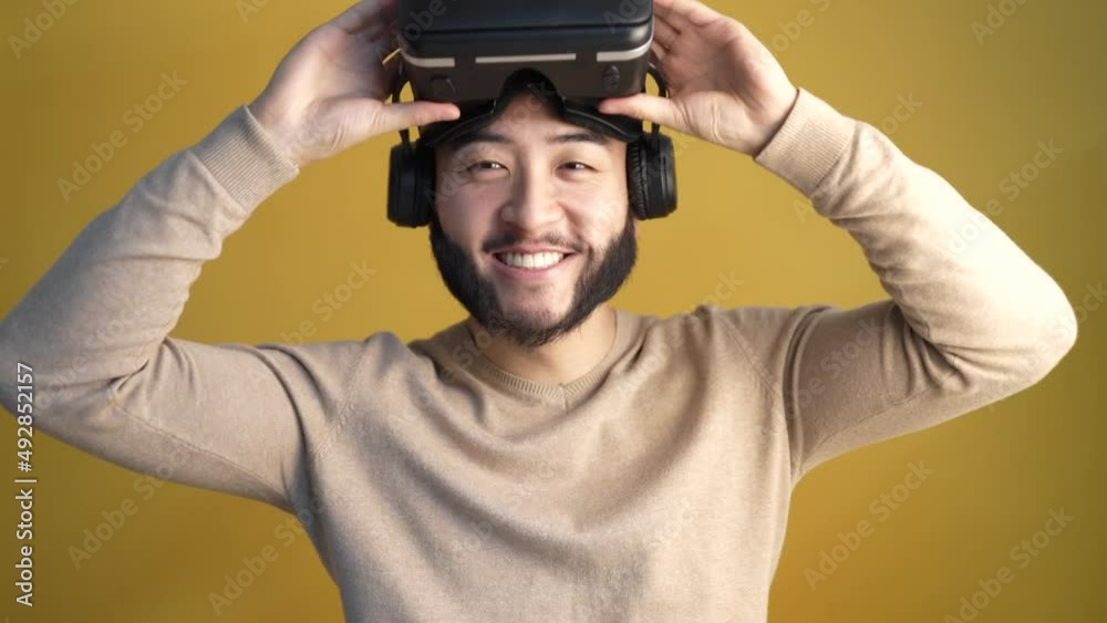 asian man virtual reality glasses slow motion, on yellow background, metaverse. asian man virtual reality glasses slow motion, on yellow background, metaverse.