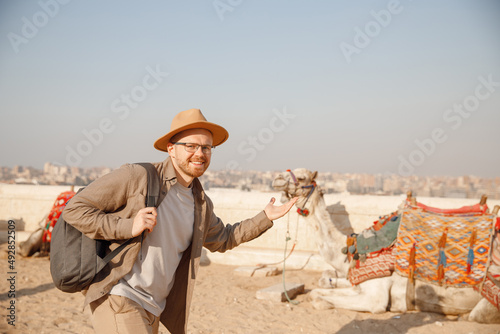 Tourist man in hat with camel background pyramid of Egyptian Giza, sunset Cairo, Egypt