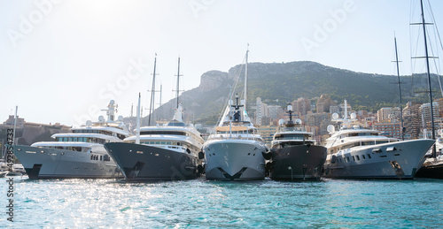 Super Yachts moored in Monaco harbour with Monaco landscape on a background 
