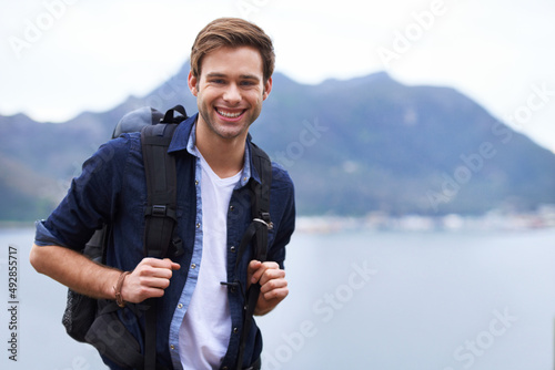 Best hiking destination. Portrait of a handsome young man standing with a backpack in the outdoors.