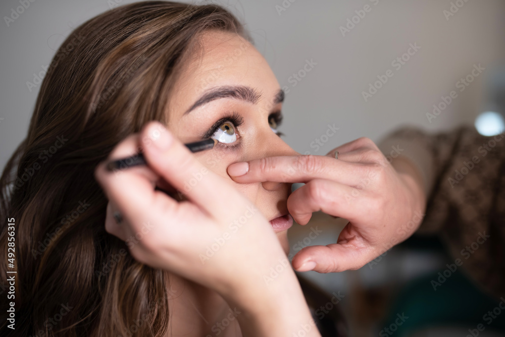 Make-up artist applies eyeliner to the girl's lower eyelid Make-up artist applies eyeliner to the girl's lower eyelid