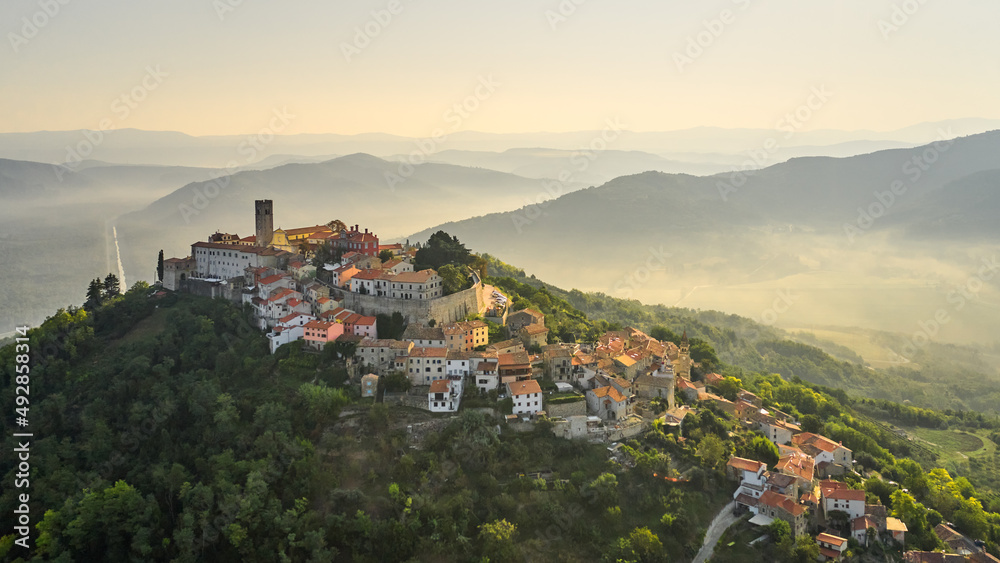 A delightful sleeping ancient fortress city on a high hill in the morning fog. Croatia. Motovun. Shooting from a drone.