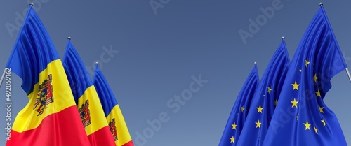 Three flags of European Union and Moldova on flagpoles on the sides. Flags on a blue background. Place for text. EU, Europe. Chisinau. Commonwealth. 3D illustration.
