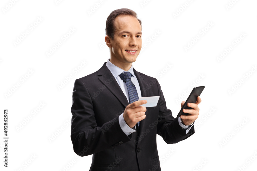 Businessman using a credit card and a mobile phone and looking at camera Businessman using a credit card and a mobile phone and looking at camera