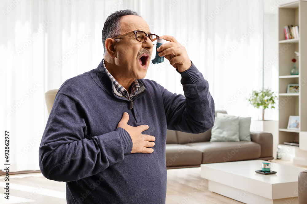 Mature man using an inhaler at home Mature man using an inhaler at home