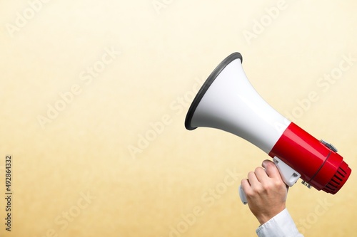 Megaphone in woman hands on color background.
