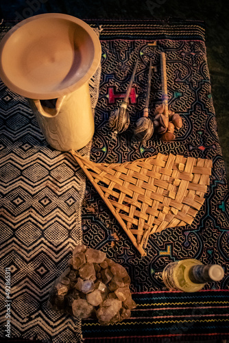 Sao Paulo, SP, Brazil - March 12 2022: Altar for ceremony composed of two fabrics with Shipibo prints, jar with Ayahusca tea, maracas, fan made of straw and crystal stone detail