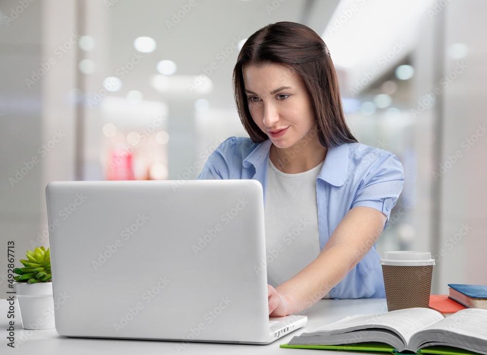 Smiling dreamy confident businesswoman sitting at work desk with laptop Smiling dreamy confident businesswoman sitting at work desk with laptop