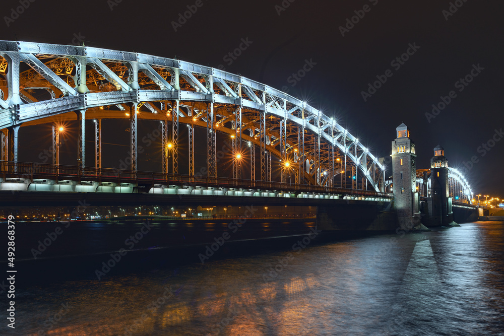 Naklejka premium the beautiful metal bridge of Peter the Great across the Neva River in St. Petersburg against the night sky