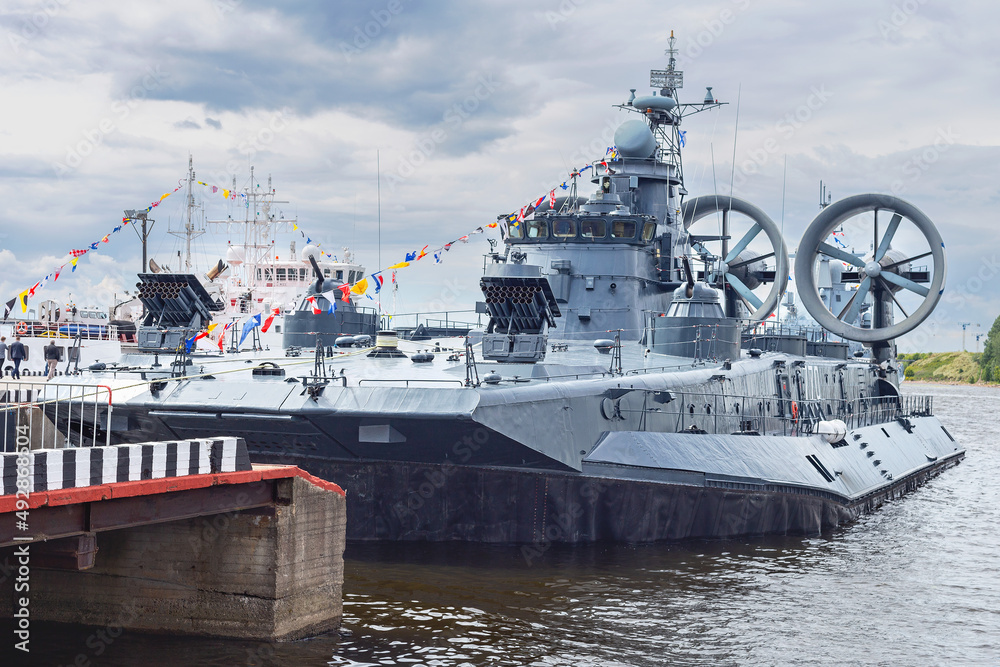 view of a military ship parked in the port of the Russian city of St. Petersburg against a blue cloudy sky