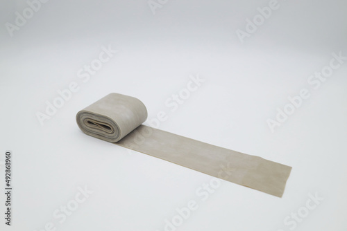 A rolled-up coil of rubber tourniquet to stop the blood. Elastic beige ribbon for sports, fitness and stretching.