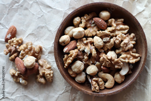 A mixture of nuts in a wooden bowl on a beige background. Dried nuts.