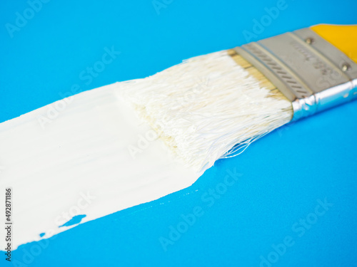 brush with white paint draws space for text on blue background