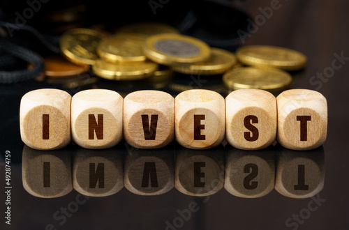 On a black surface are coins and cubes with the inscription - INVEST © Dzmitry